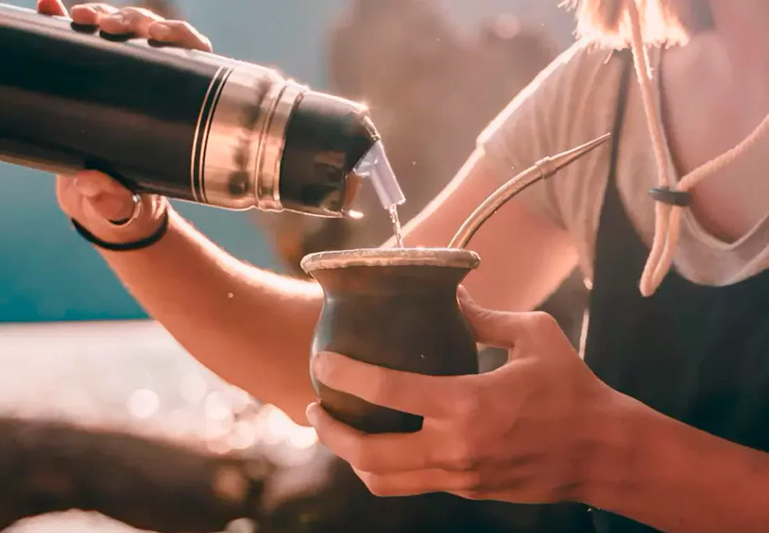 Persona cebando un mate con termo de agua