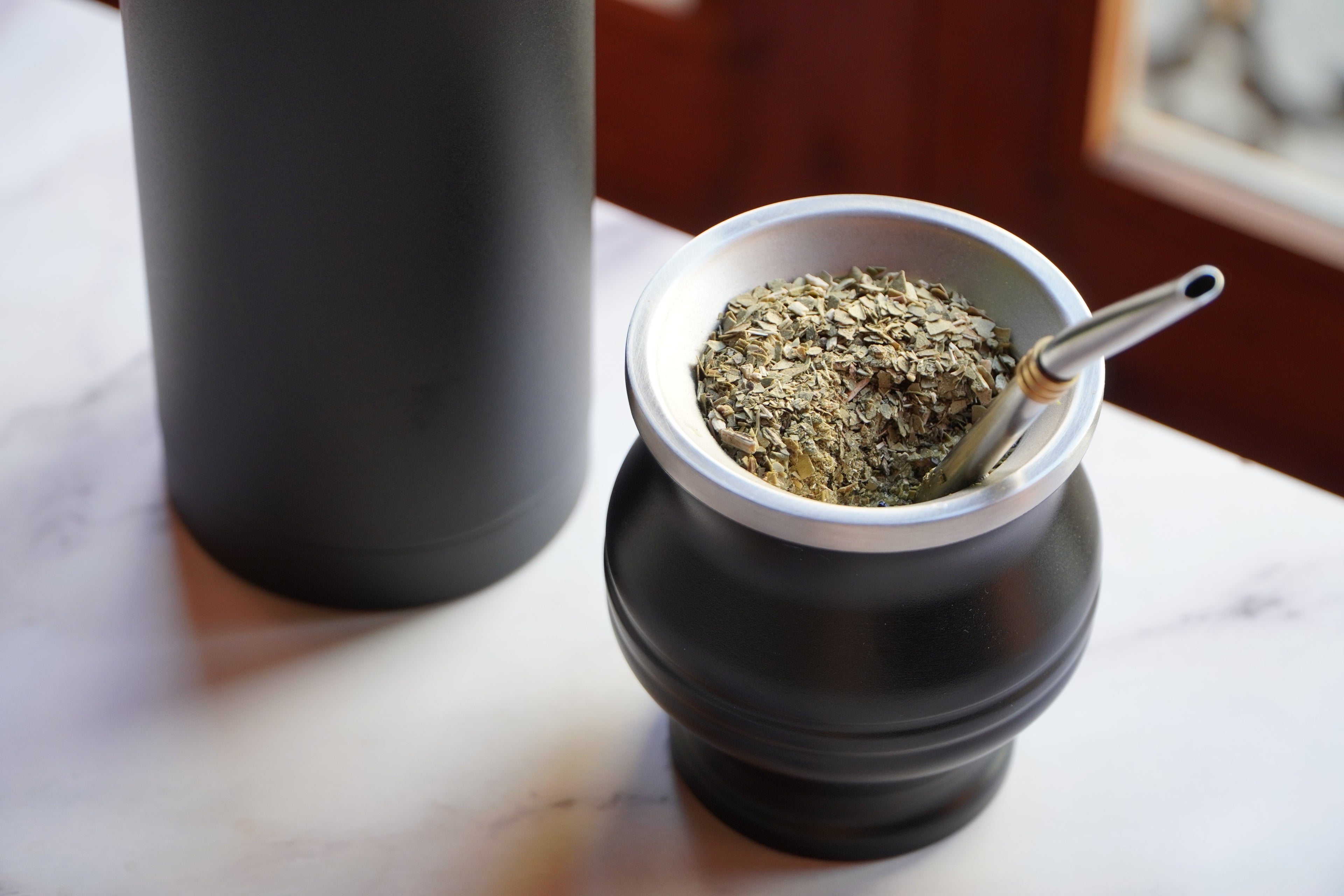 Mate de acero inoxidable con yerba mate organica en una mesa