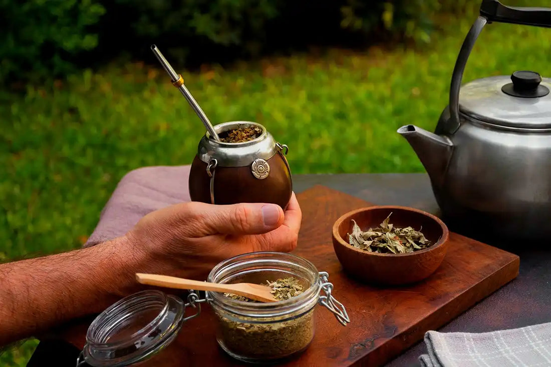 Mate preparado en primer plano con un calentador y yerba de fondo