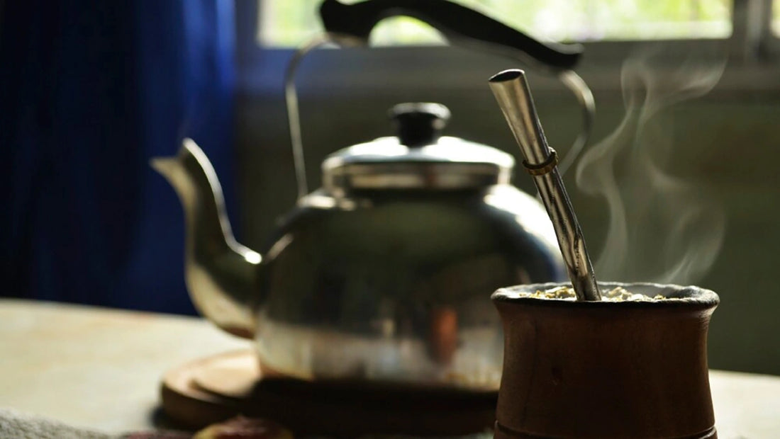 Mate servido arriba de una mesa y un hervidor de fondo