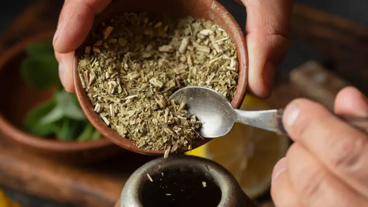 Persona colocando yerba en un recipiente de mate con cuchara